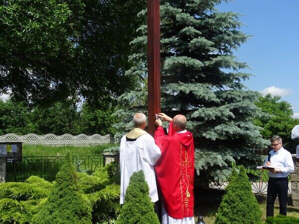Zdjęcie księży umieszczających ka krzyżu pamiątkową tabliczkę